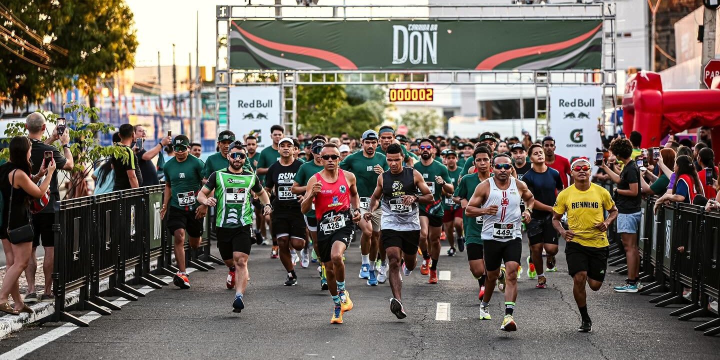Largada da Corrida da Don, com corredores de camiseta verde sob o pórtico DON