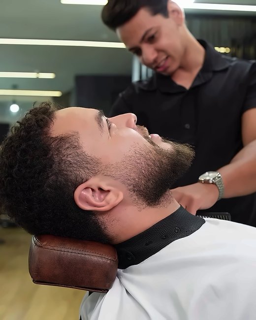 Barbeiro finalizando a barba do cliente reclinado