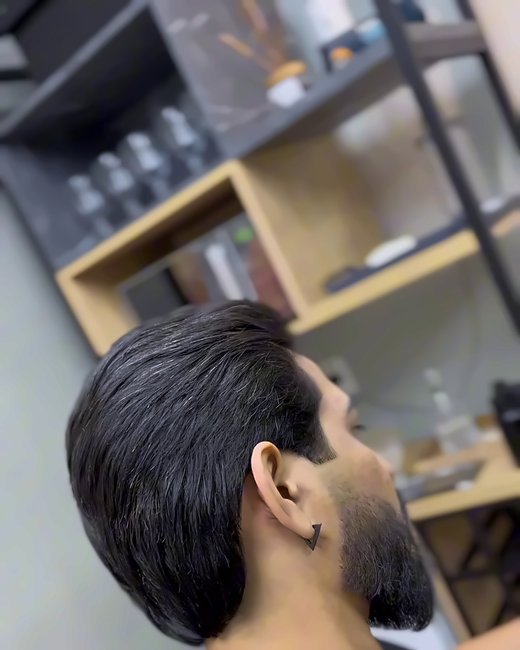 Cliente de perfil com barba desenhada e cabelo penteado