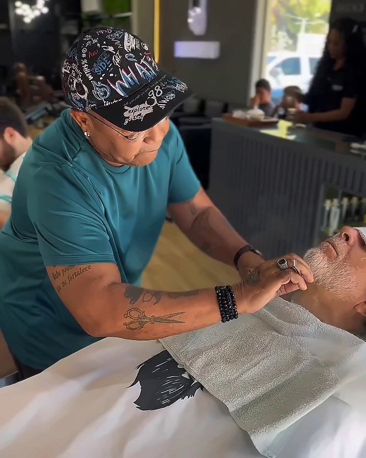 Barbeiro fazendo a barba do cliente na navalha, com toalha